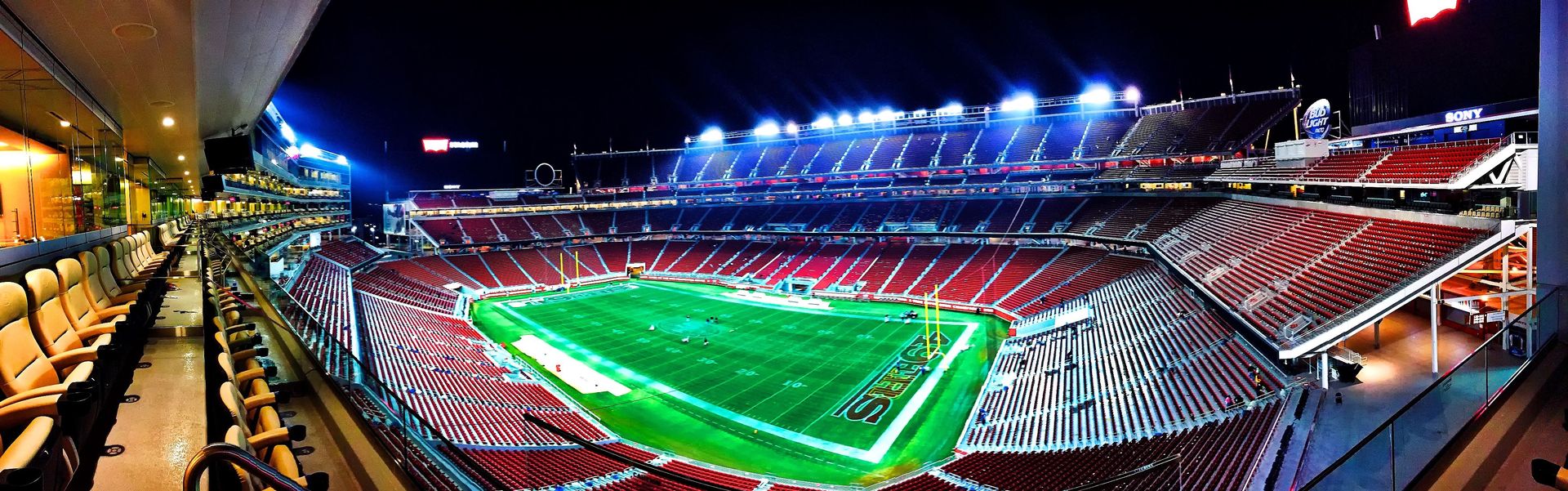 A football stadium filled with fans under floodlights at night.